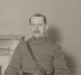 Black-and-white photograph of Leonard P. Ayres in a U.S. Army officer's uniform with a shoulder strap, seated in an office with a marble fireplace behind him (detail of a larger office photograph).