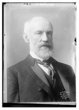 Black-and-white studio portrait of G. Stanley Hall, an older man with white hair and a full white beard, wearing a dark suit, waistcoat and patterned tie; a photographer's blind stamp is at lower right.