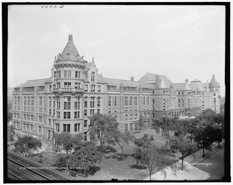 Black-and-white Detroit Publishing Co. photograph, c. 1900–1910, of the American Museum of Natural History in New York, the 1932 congress venue: a long stone building with a turreted corner tower, seen from above with trees on its lawn and an elevated railway track in the foreground.